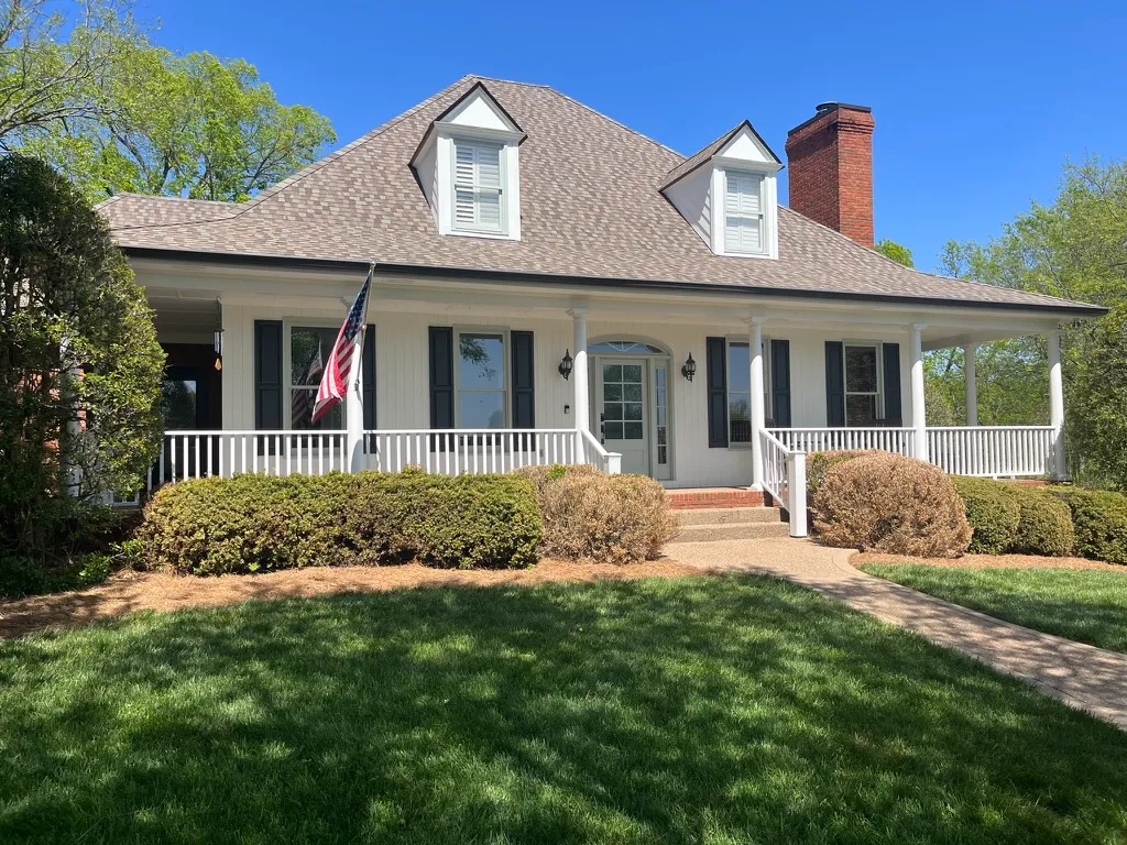 Residential exterior with painted siding, white porch trim, and shutters